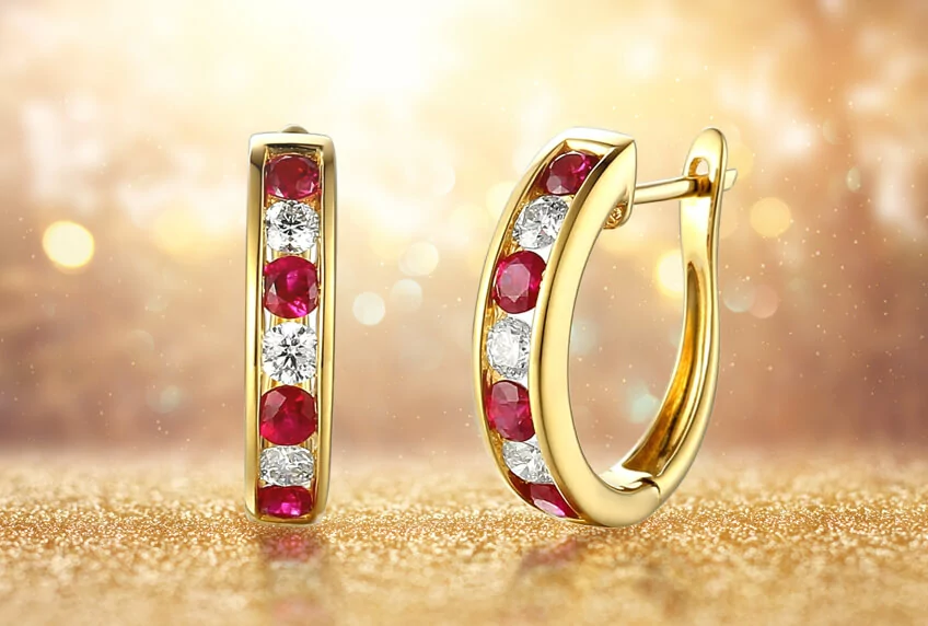 July Ruby Birthstone advertising banner displaying a pair of 18ct Yellow Gold Ruby & Diamond Hoop Earrings on a gold sparkly background.